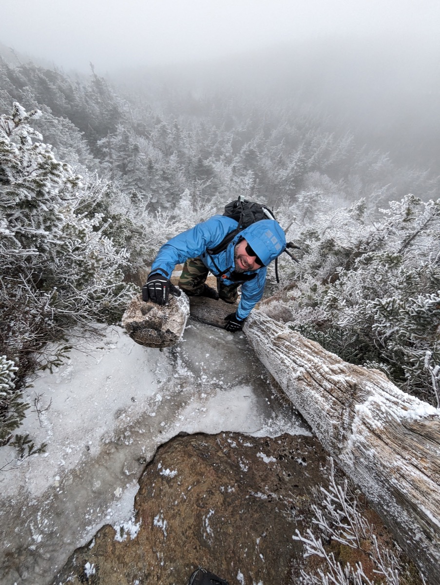 Yoni Ryabinski scrambling up an ice-covered ridge in winter